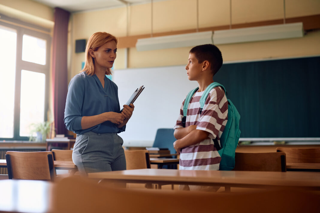 Elementary school teacher talking to her student after a class int he classroom.